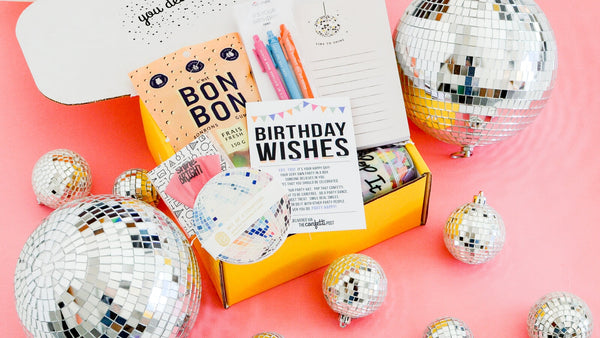 Shop Birthday Gift Box Delivery Ideas_Open box filled with birthday gifts: socks, candle, birthday cake pretzels, balloon, and confetti