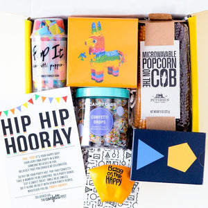 Game Night Theme Care Package for corporate clients and employee appreciation_two popcorn cobs, primary color shapes designed card game box, yellow cube puzzle box with rainbow pinata, bag of gummy bears, confetti popper, and yellow balloon