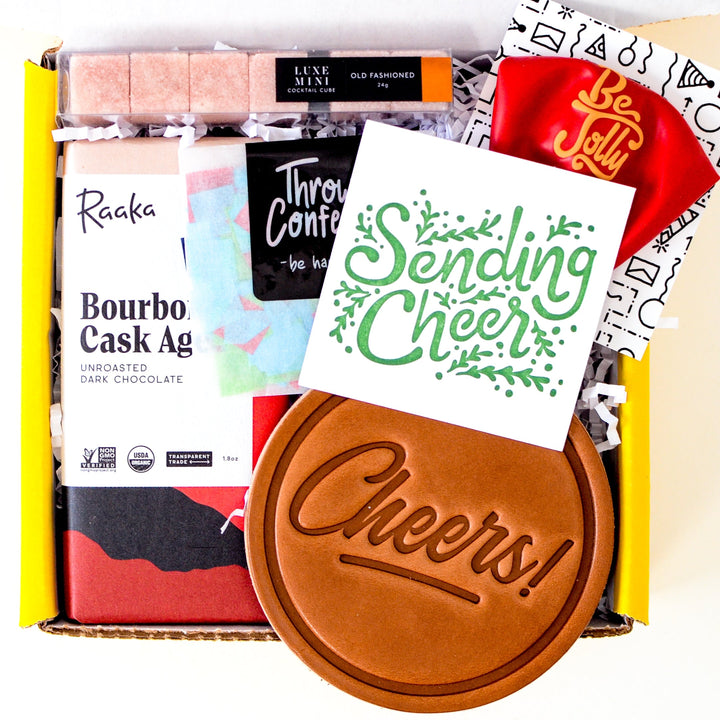 Bourbon Whiskey Themed Small Gift box: Filled with red and black chocolate bar, brown leather sheers stamped coaster, pack of square sugar cubes with label old fashioned. Plus Sending Cheer card, confetti pack, and red balloon with words be jolly