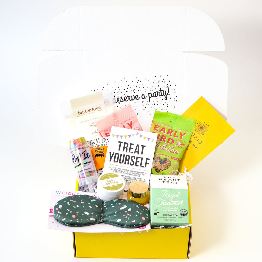 Fun assortment of self care gifts packed as a care package inside a yellow box with the words "you deserve a party" when you open the box
