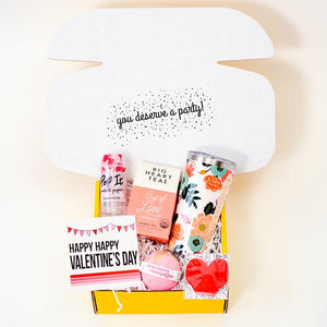 Long Distance Valentine's Day Care Package_Open Yellow Gift Box with velentine's day card and assorted gifts like a mug, bath bomb, and tea
