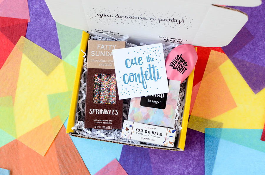 Open small congratulations gift box shown open witht he message card Cue the Confetti. On a colorful background.